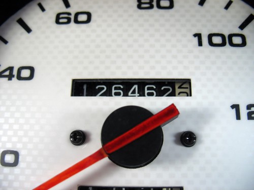 Closeup of a car's speedometer, with the odometer in the middle showing the number of miles driven for delivery and personal use.