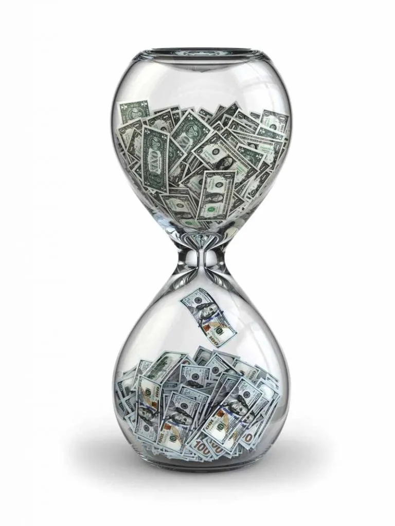 Time is money concept illustrated by an hourglass filled with one dollar bills on the top and 100 dollar bills on the bottom.