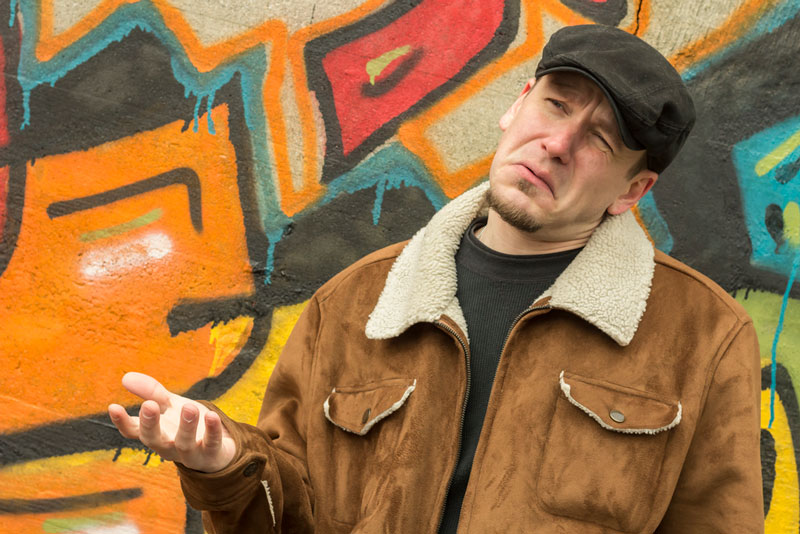 Man in a leather jacket and cap with a quizzical expression, holding a hand up looking like he's trying to decide between monetization options.