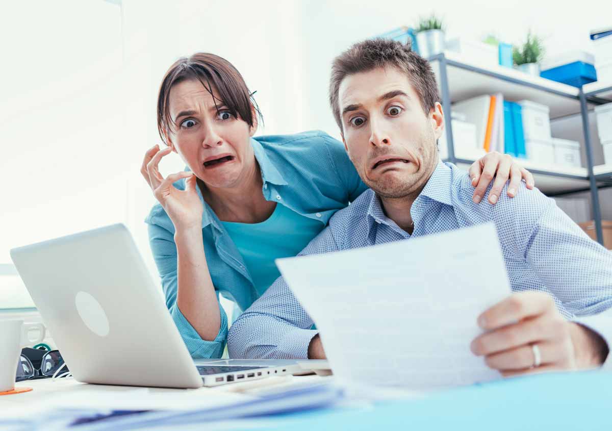 A couple sitting by their computer is looking at their tax bill with looks of horror.