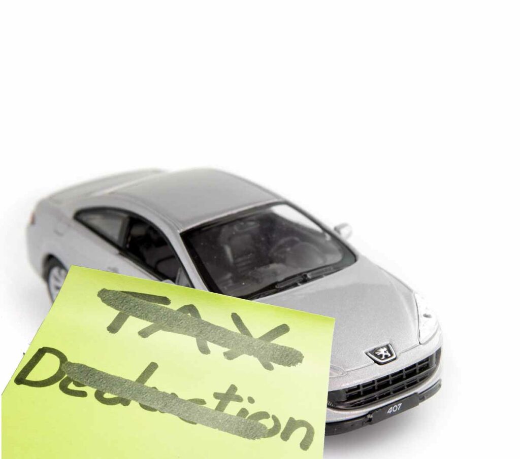 A toy car with a post it note over the side of it. The post it note has Tax Deduction written and then crossed out.