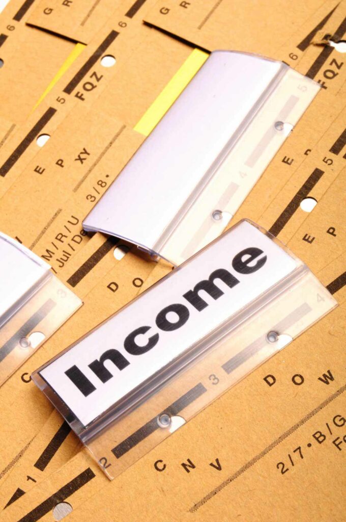 A set of file folders lying on a table with the top folder labeled Income.