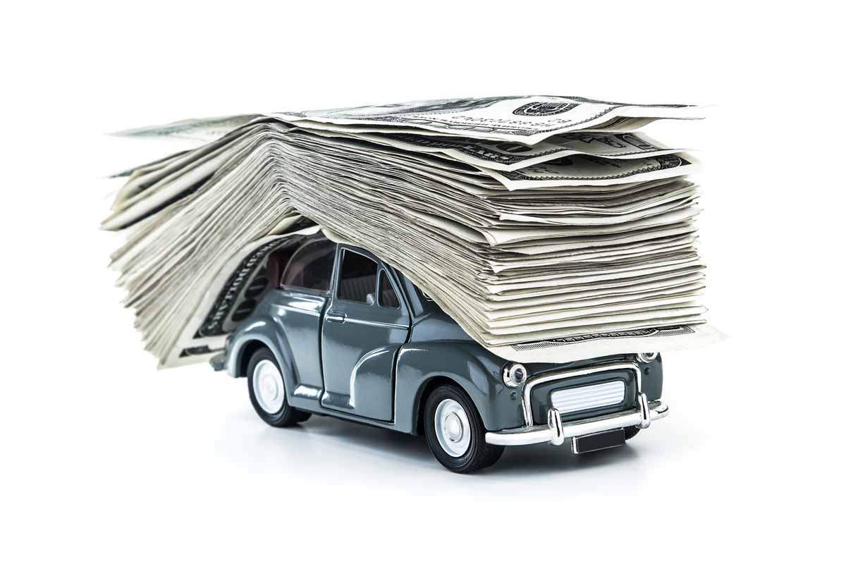 Car payment concept illustrated by a large stack of one hundred dollar bills stacked on top of a model car.