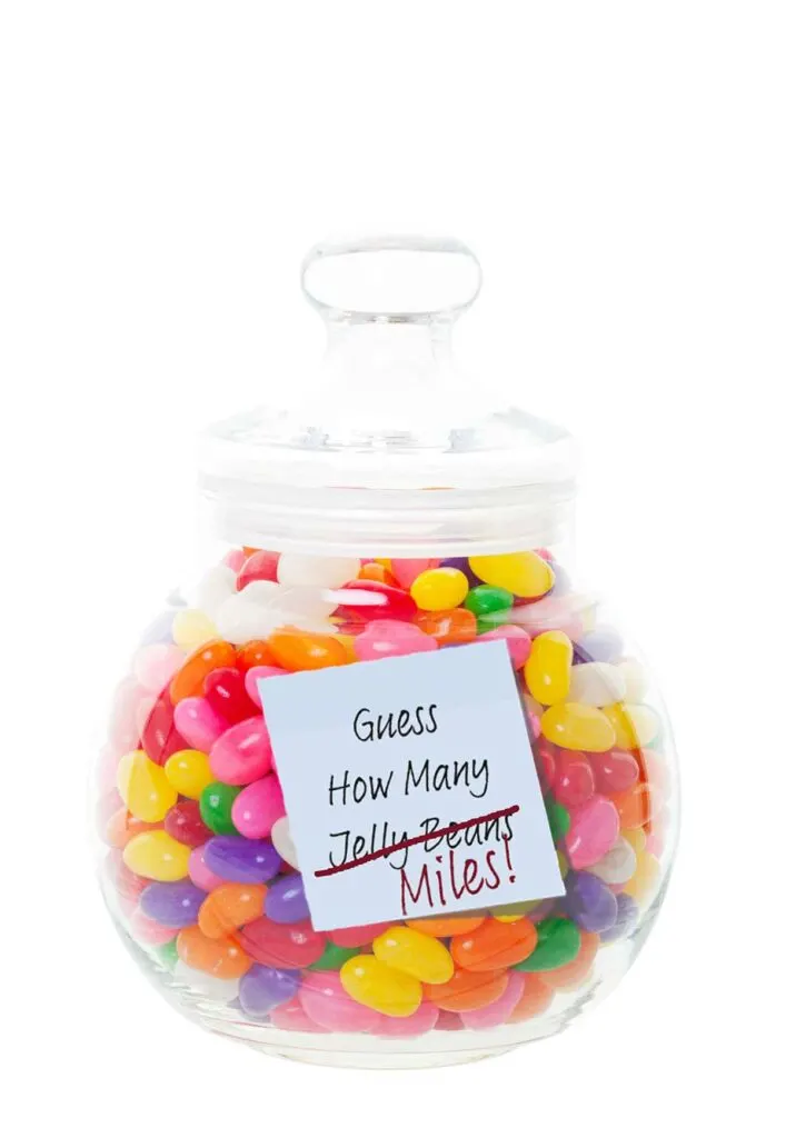 A jelly bean jar with a post it note stuck to it, the note reads Guess How Many Jelly Beans, but Jelly Beans is crossed out and Miles is scribbled below. 