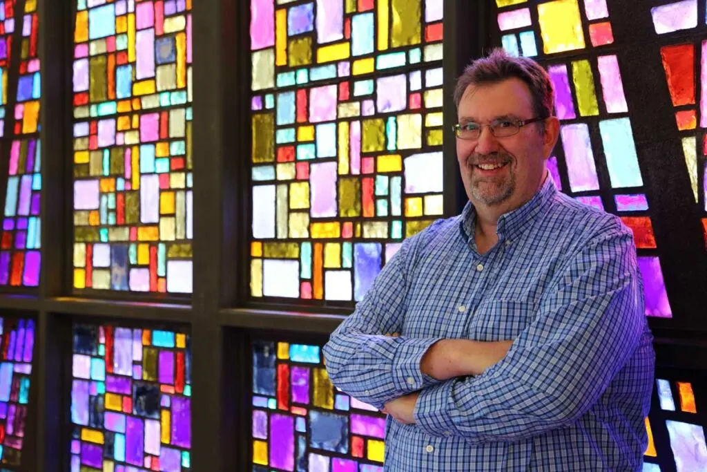 EntreCourier founder Ron Walter standing in front of a stained glass window.